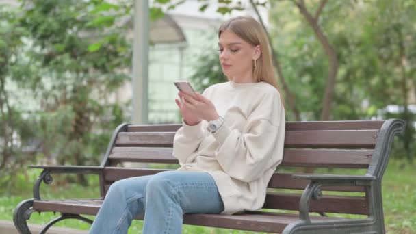 Rento Nuori Nainen Käyttää Puhelinta Istuessaan Ulkona — kuvapankkivideo
