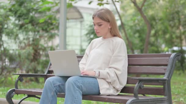 屋外で座っている間背中の痛みとラップトップを使用してカジュアルな若い女性 — ストック動画