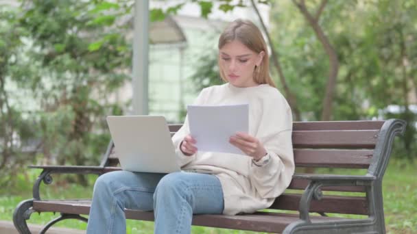 Casual Young Woman Γιορτάζοντας Ενώ Χρησιμοποιώντας Laptop Και Έγγραφα Εξωτερική — Αρχείο Βίντεο