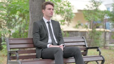 Diş ağrısı olan genç iş adamı dışarıda oturuyor.