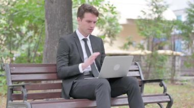 Boyun ağrısı olan genç iş adamı laptopla dışarıda çalışıyor.