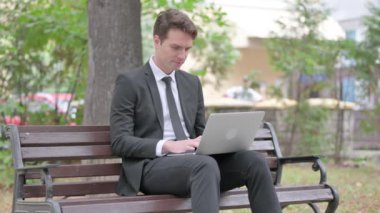 Genç İşadamı dizüstü bilgisayarla çalıştıktan sonra Bench 'i açık havada bırakıyor.