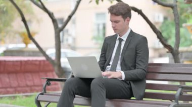 Diş ağrısı olan bir iş adamı laptopla dışarıda çalışıyor.
