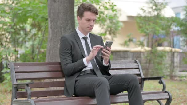 Jovem Empresário Comemorando Sucesso Line Telefone Enquanto Sentado Livre — Vídeo de Stock
