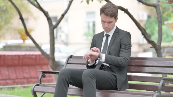 Empresário Usando Relógio Inteligente Enquanto Sentado Banco — Vídeo de Stock
