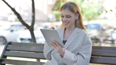Genç İşkadını Tablet 'te kutlama yaparken Bench' te oturuyor.