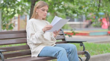 Dışarıda Otururken Belgeleri Okuyan Genç Kadın