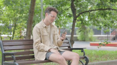 Modern Genç Adam Akıllı Telefon 'da Kayıpla Karşı Karşıya Geçerken Benç' te
