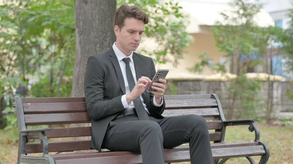 Jovem Empresário Usando Telefone Enquanto Sentado Livre — Fotografia de Stock