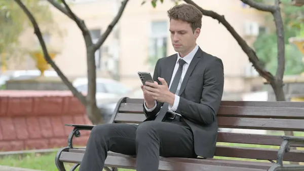 Businessman Using Phone While Sitting Bench — Fotografia de Stock