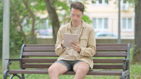 Casual Young Man Χρησιμοποιώντας Tablet Ενώ Κάθεται Ένα Πάγκο — Φωτογραφία Αρχείου