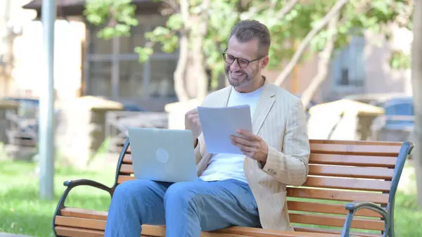Homem Meia Idade Comemorando Enquanto Trabalhava Laptop Documentos Livre — Fotografia de Stock