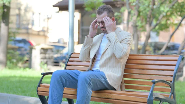 厌倦了的中年男人坐在户外头疼 — 图库照片