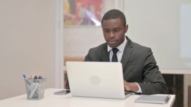 Ofiste otururken dizüstü bilgisayarda çalışan Afrikalı İşadamı