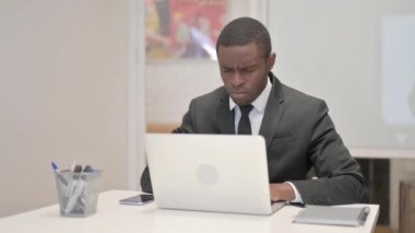 Ofiste otururken dizüstü bilgisayar kullanan Afrikalı İşadamı öksürüyor