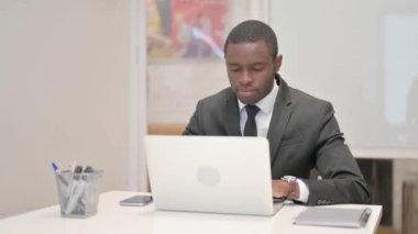 Ofiste dizüstü bilgisayarla çalışırken kameraya bakan Afrikalı İşadamı