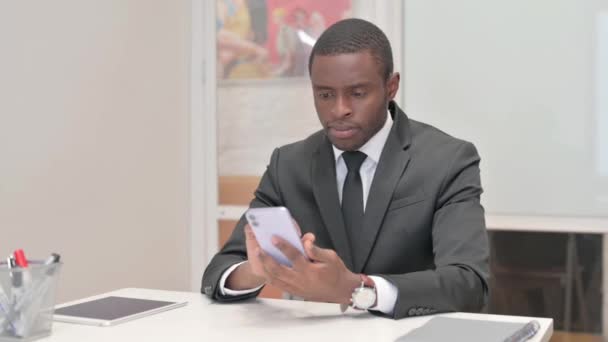 Empresário Africano Usando Telefone Enquanto Sentado Escritório — Vídeo de Stock