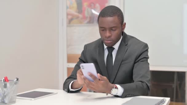 African Businessman Zszokowany Stratą Telefonu Podczas Siedzenia Biurze Ławce — Wideo stockowe