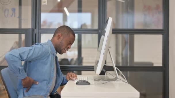 デスクトップで働く背中の痛みを持つアフリカのビジネスマン — ストック動画