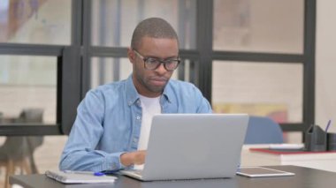 Ofiste Dizüstü bilgisayarla çalışırken kameraya gülümseyen Afrikalı İşadamı