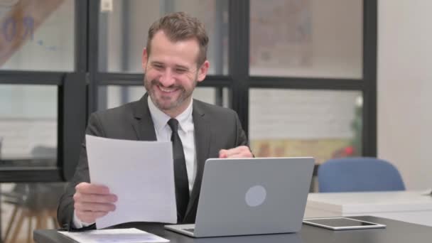 Geschäftsmann Feiert Während Papierkram Erledigt — Stockvideo