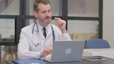 Bilgisayarla görüntülü konuşma yapan orta yaşlı bir doktor.