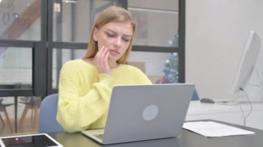 İş yerinde diş ağrısı olan genç sarışın kadın.