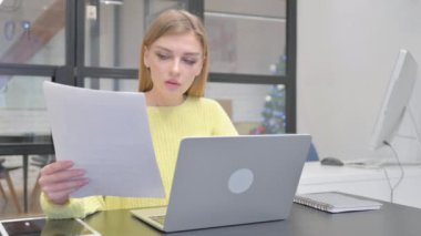 Genç Sarışın Kadın Belgeler ve Laptop üzerinde çalışırken Kutlama Yapıyor