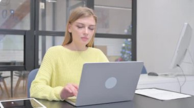 Genç Sarışın Kadın Dizüstü bilgisayarla çalışırken kameraya bakıyor