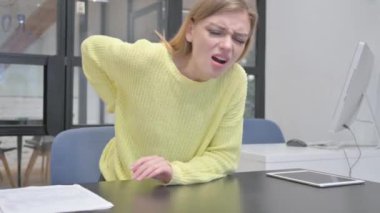 Genç Sarışın Kadın ayağa kalkmaya çalışırken sırt ağrısı çekiyor.