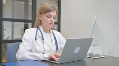 Dizüstü bilgisayarda çalışırken kameraya bakan kadın doktor