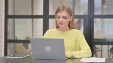 Dizüstü bilgisayarda çalışırken kameraya gülümseyen sıradan yaratıcı kadın