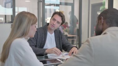 Ofiste kendinden emin genç iş adamları konuşuyor.