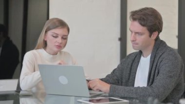 ofiste bilgisayar üzerinde çalışan genç bir çift