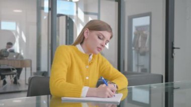 Çalışırken yazan genç kadın.