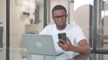 Akıllı telefon ve dizüstü bilgisayarla çalışan Afro-Amerikan Adam