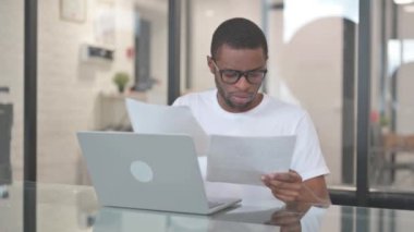 Laptop üzerinde çalışırken evrak işi yapan Afrikalı Amerikalı adam