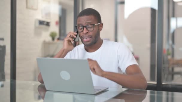 Hombre Afroamericano Hablando Por Teléfono Mientras Trabaja Ordenador Portátil — Vídeo de stock