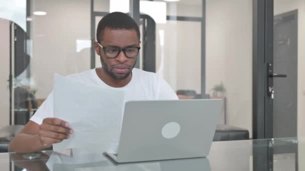 Hombre Joven Africano Celebrando Mientras Usa Ordenador Portátil Los Documentos — Vídeos de Stock