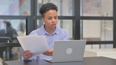 Laptop Kullanılırken Karışık Irk Kadını Belgeleri Okuyor