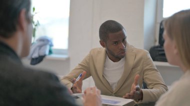 Toplantı sırasında takım arkadaşlarıyla konuşan Afrikalı Adam