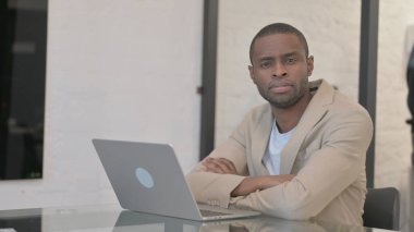 Ofiste dizüstü bilgisayarla çalışırken Afrikalı Amerikalı Adam Kameraya Bakıyor