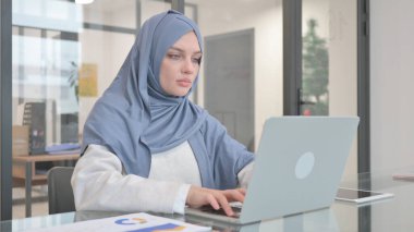 Dizüstü bilgisayarda çalışan tesettürlü kadın
