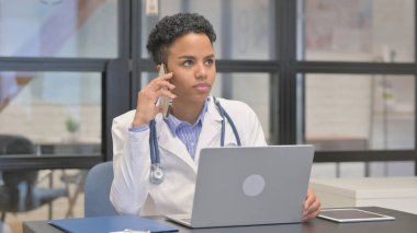 Karışık Yarış Kadın Doktoru Telefonda konuşuyor ve dizüstü bilgisayar kullanıyor