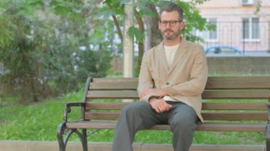 Migreni olan genç adam Bench 'in dışında oturuyor.