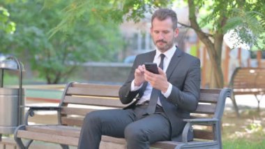 Genç İşadamı Dışarıda Otururken Telefonda Başarıyı Kutluyor