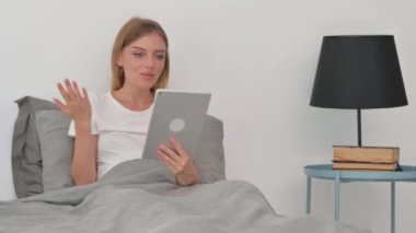 Yatakta otururken Tablette Video Sohbeti Yapan Genç Kadın