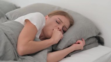 Hasta genç kadın yatakta yatarken öksürüyor.