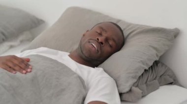 Afrikalı adam uyanıyor ve yataktan kalkıyor.