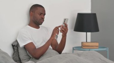 Yatakta oturan Afrikalı Adam Telefonda Kayıp 'tan Üzgündü